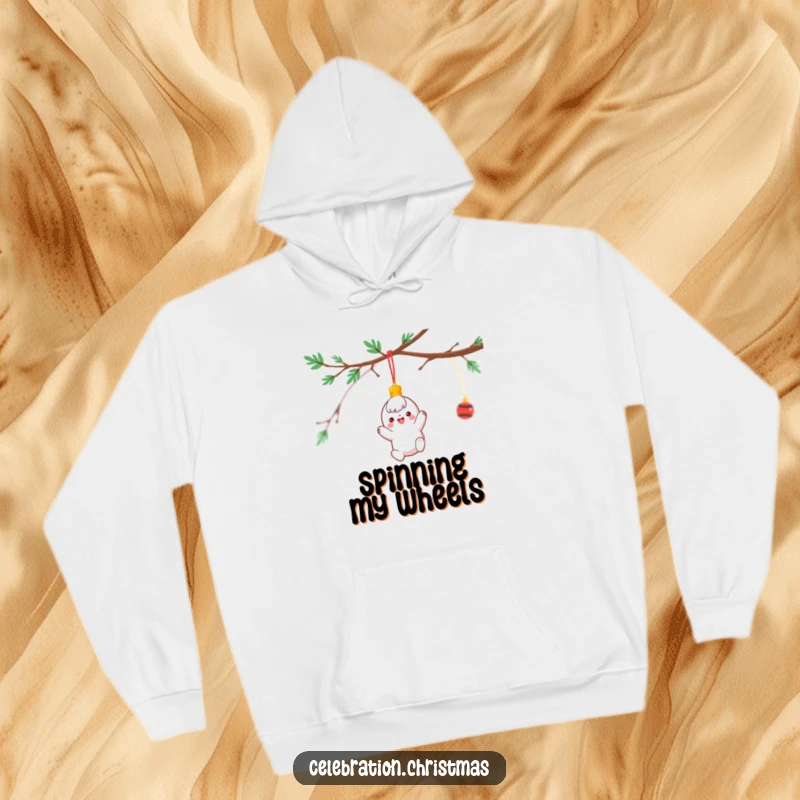 Funny Hoodie depicting a bright ornament character cheerfully spinning while dangling from a decorated branch, cozy holiday wear.